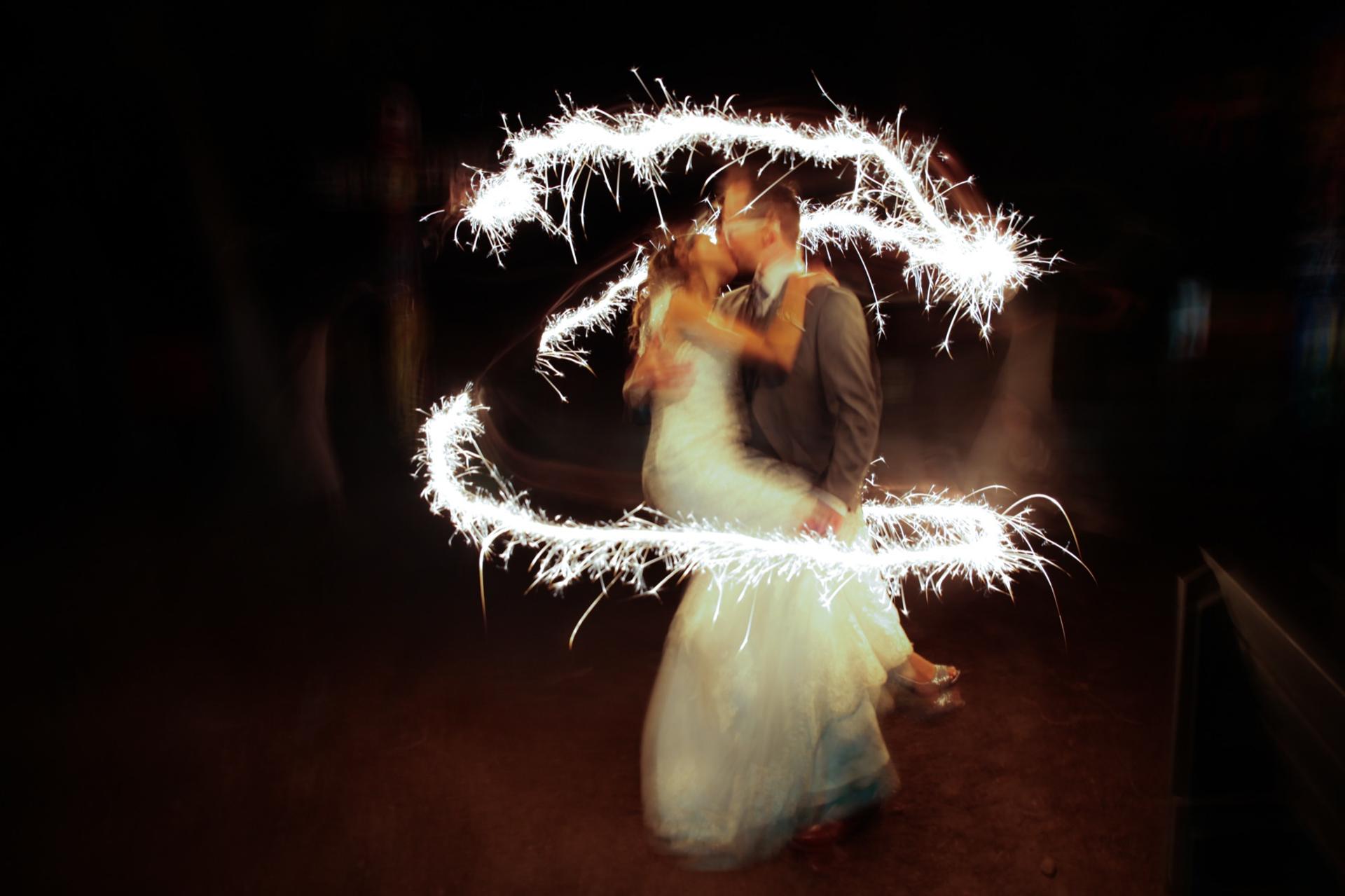 Long exposure of a couple embracing at night inside a circle traced by sparklers