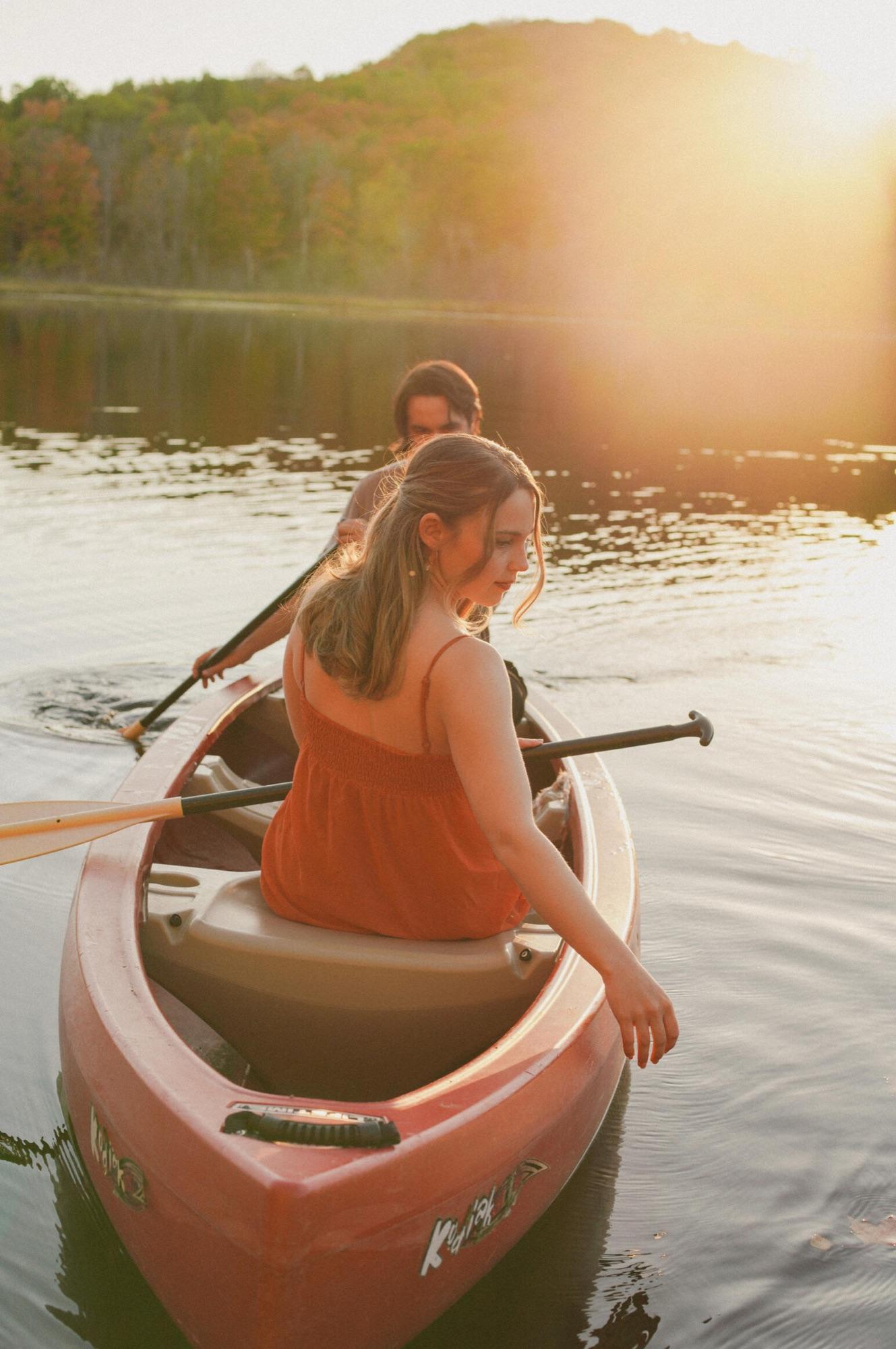 Two people paddling a canoe on the lake in low golden light