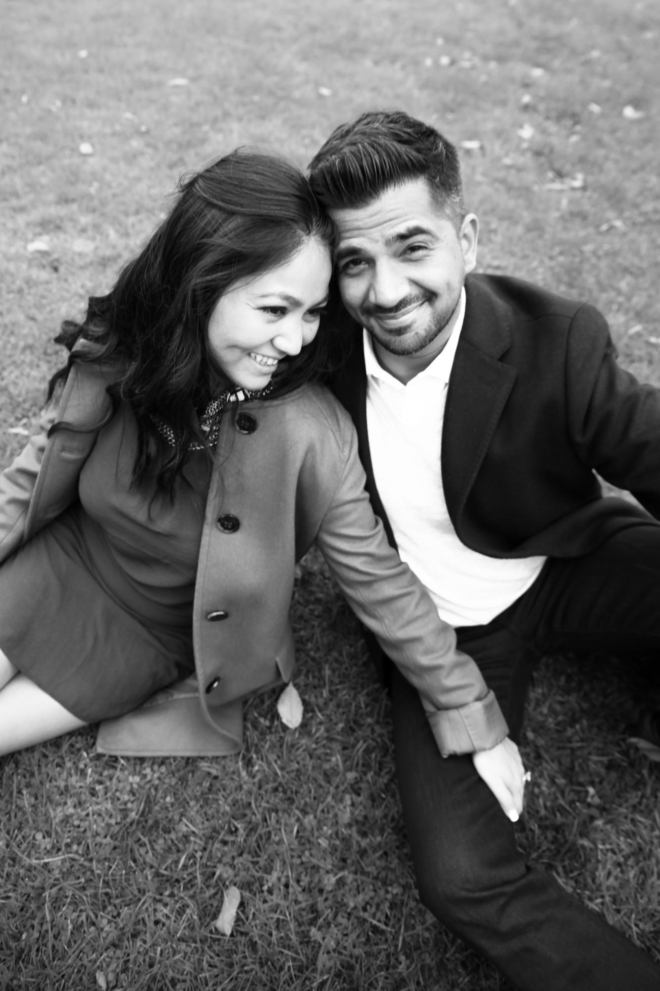 Black and white portrait of a couple sitting on autumn grass, heads together, laughing