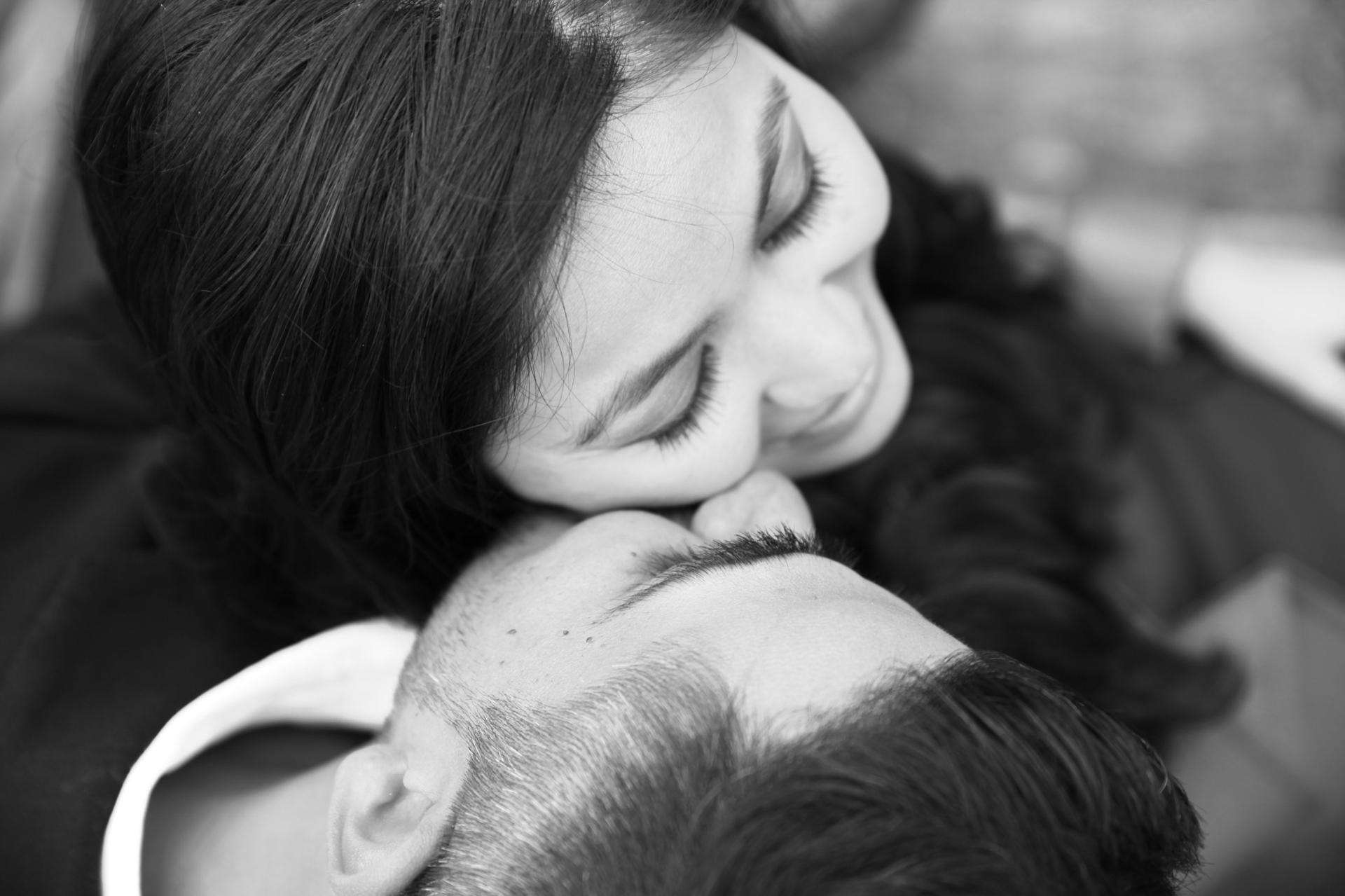 Close black and white frame of a woman resting her chin on her partner's head with her eyes closed