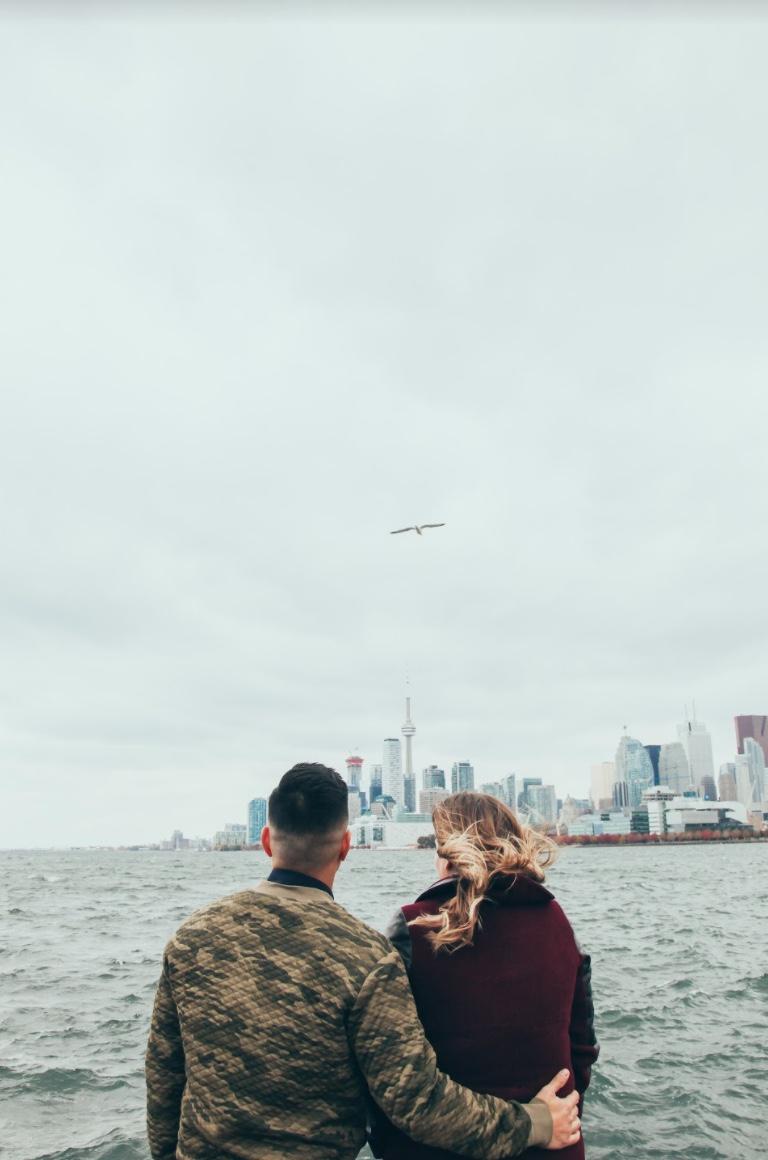 Couple seen from behind looking across the water at a city skyline