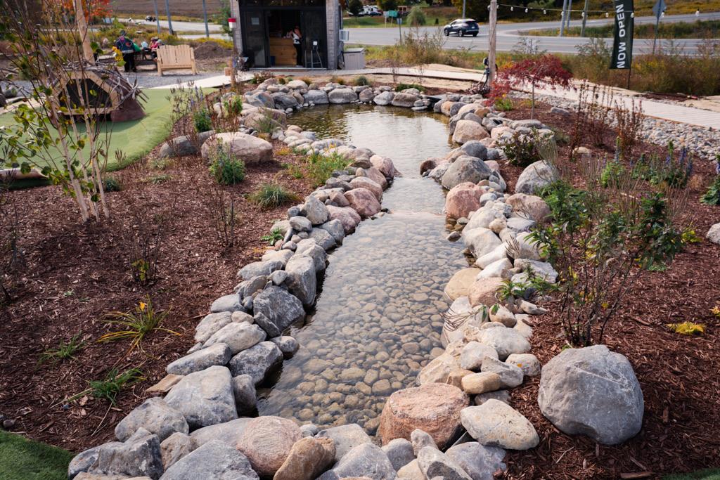A stone-lined stream running through the course between fresh plantings