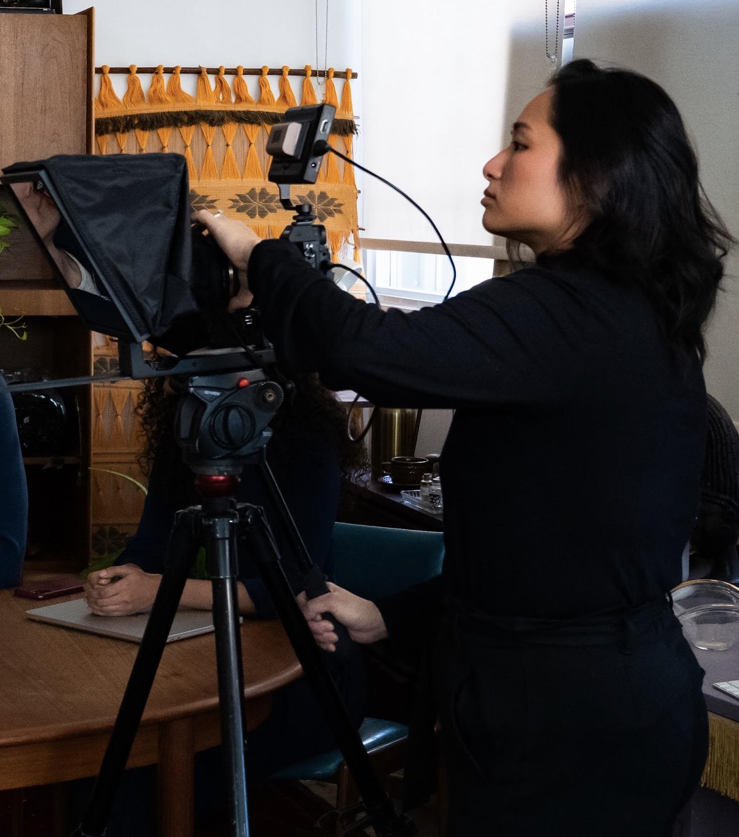 Rosa Park setting up a camera and teleprompter on a tripod for an interview