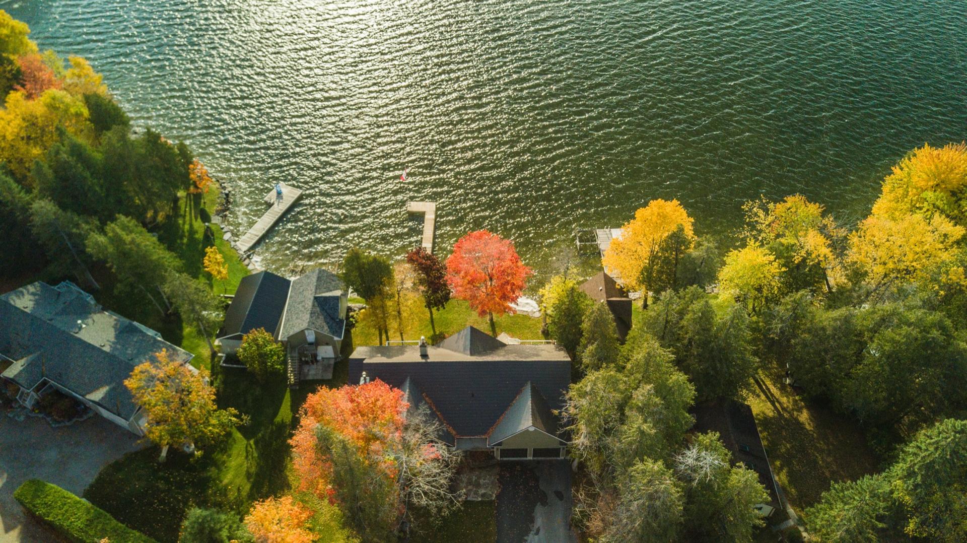 Overhead aerial view of lakefront properties with private docks and turning autumn trees