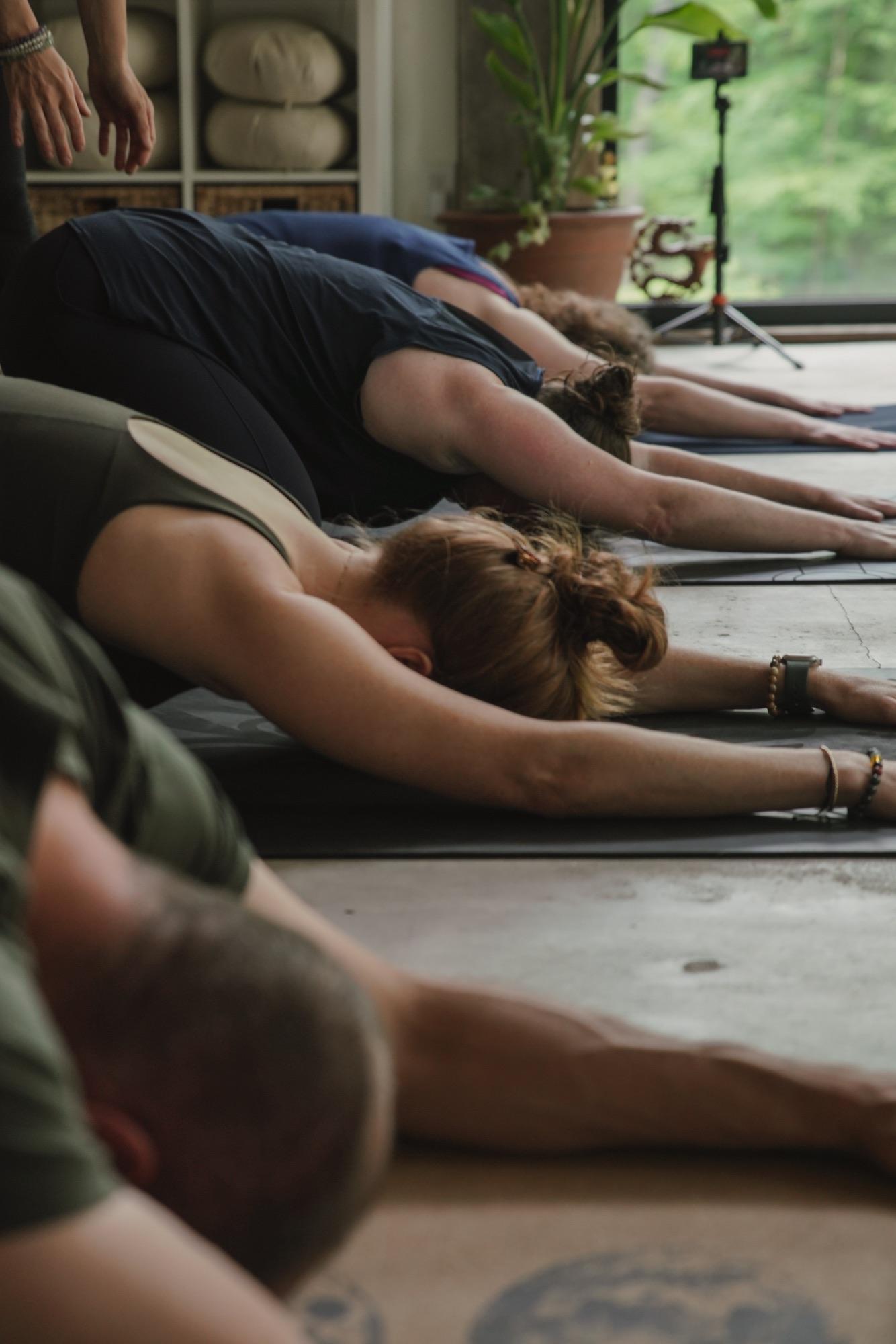 Row of students resting in child's pose along the studio floor